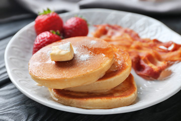 Tasty breakfast with pancakes, bacon and strawberry on plate