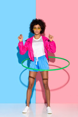 Sporty woman posing while exersizing with hoop and looking at camera on pink and blue background © LIGHTFIELD STUDIOS