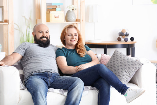 Overweight couple watching tv at home