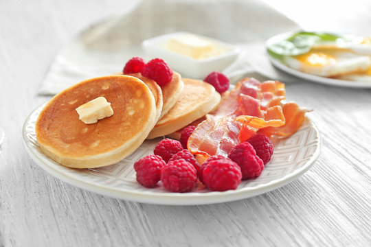 Tasty breakfast with pancakes, bacon and raspberry on plate