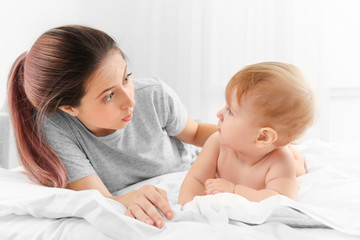 Young mother and her cute baby on bed at home