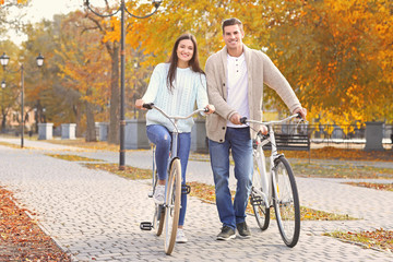 Young couple riding bicycles in park