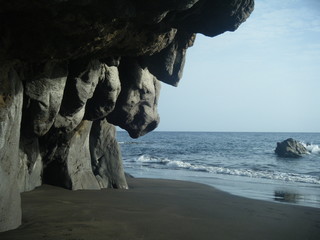 cueva de piedra volcanica en una playa de arena negra en la isla de Gran Canaria