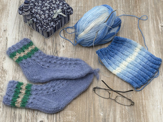 Knitted socks and scarf on a wooden background. 
