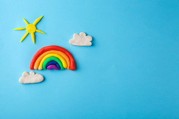 Plasticine rainbow, sun and clouds on color background