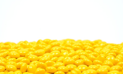 Yellow sugar coated tablets pills on white background with copy space. Medicine for treatment constipation.