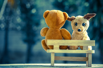 two bear dolls on wooden bench with dramatic tone