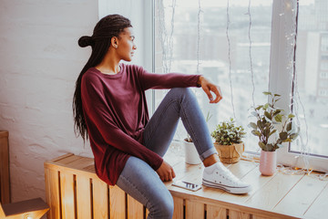 Dreamful African woman looking out window