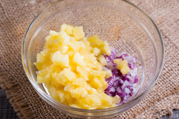 Pineapple salsa in a glass bowl with onion. Preparation