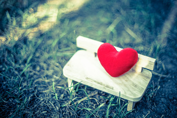 red heart on wooden bench with dramatic tone