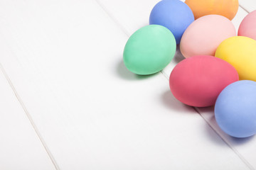 Easter composition with colored eggs on wooden white background with copy space.