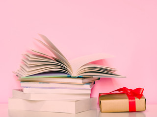 decoration concept for christmas and new year and congratulation event by red and gold wrapped gift box and set of book with pink pastel colour background