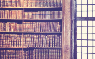 Vintage toned old books on wooden shelves, education concept background.