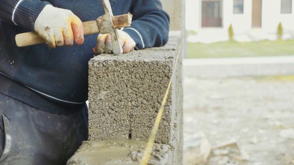 Construction worker builds brick wall, closeup view at construction site