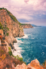 Amazing sunset seascape during a storm, wild mediterranean sea coast with waves breaking against rocks, vertical image, Dubrovnik, Croatia
