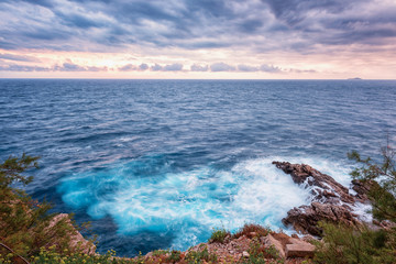 Fototapeta na wymiar Amazing sunset seascape during a storm, wild mediterranean sea coast with waves breaking against rocks, Dubrovnik, Croatia