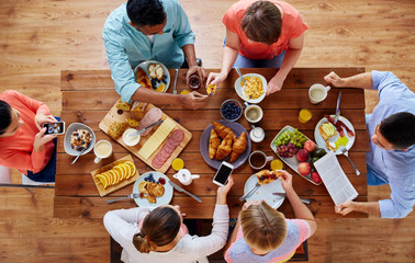 people with smartphones eating food at table