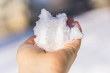 Close-up of a hand holding a snow ball on a cold winter day. Shallow depth of focus. Winter concept.