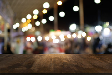 Empty wood table top and blur of night market background/selective focus .For montage product display.