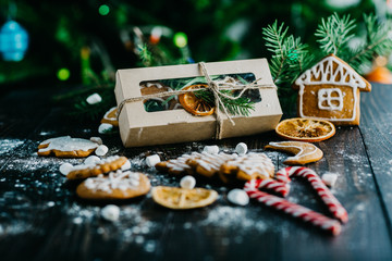 gingerbread, craft gift packaging, candy canes, fir branches on dark background