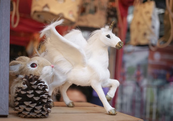 Naklejka na ściany i meble Unicorn. Animal fur props for interior decoration is on the wooden shelf with rabbit. Replica of the realistic animal miniature.