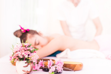 Obraz na płótnie Canvas Flower jar with woman getting massaged blurred on background