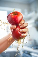 A male hand squeezes fresh juice. Pure apple juice pouring out from fruit into glass