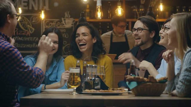 Diverse Group of Young People Have Fun in Bar, Talking, Telling Stories and Jokes. They Drink Various Drinks. They're in the Stylish Hipster Establishment. Shot on RED EPIC-W 8K Helium Cinema Camera.