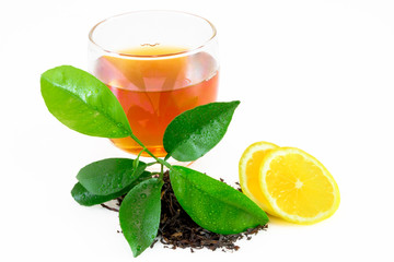 Dry black tea leaves, lemon leafs, tea on glass isolated on white