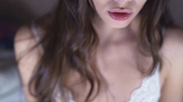 Face of sexy brunette close-up. A young woman with long curly hair flirts with the camera. eroticly opens his mouth. chubby female lips. 4k