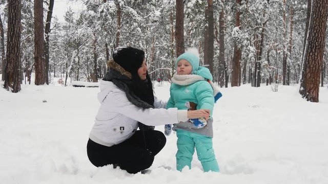 Happy woman and child playing with snow in winter park. Holidays in slow motion.