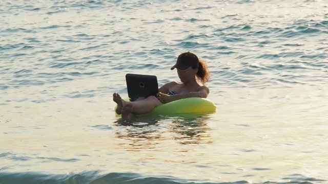 A girl is swimming with a laptop