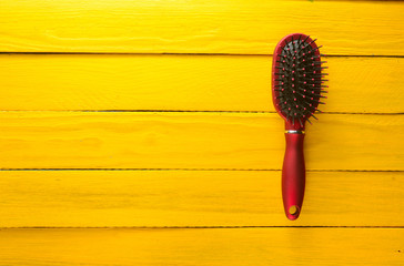 Fashionable female comb for hair care on a yellow wooden table. Trend of minimalism. Copy space....