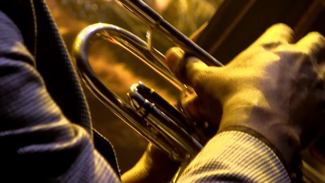Jazz singer plays on a trumpet in the dark with a yellow glow