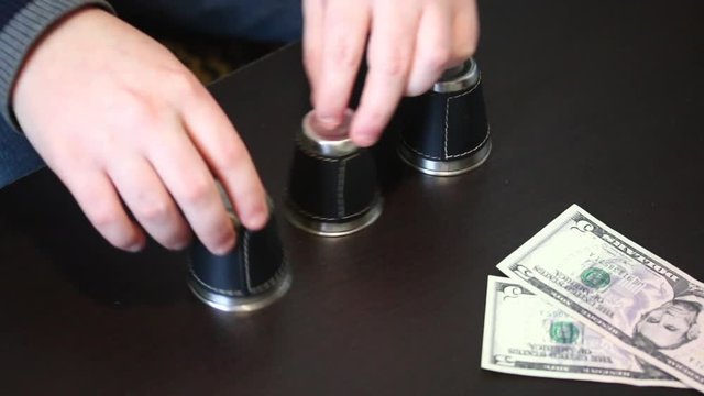 Thimblerig. A man hides a pea under one of the glasses, moves them on the table. The player points to the glass, but does not guess, and gives the win to the presenter. Cups and balls trick