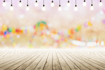 Empty wooden table with light bulb in night party background blurred.