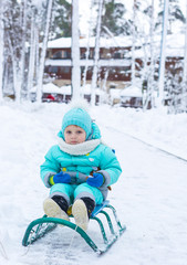 Сhild is sitting on a sled in a winter park