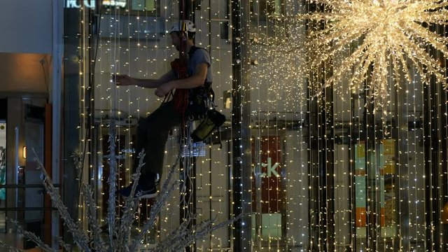 Industrial climber mounts Christmas decorations in the unsupported space in the shopping center