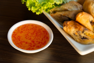 Sweet and spicy Sauce for Veg, Spring rolls in white bowl on dark wooden table