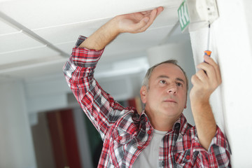 male technician on ladder repairing sign