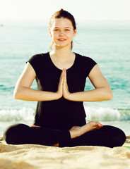 Fototapeta na wymiar Fitness woman in black T-shirt is sitting and doing yoga