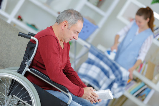 man on wheelchair and nurse helping with ironing
