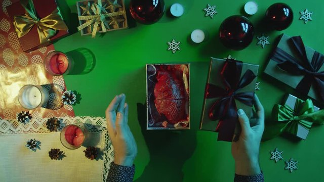 Top down shot of man opening New Year gift box with real human heart inside on table with chroma key