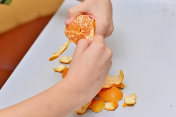boy cleanses tangerines and eats them at home in the kitchen. Four years boy eat a mandarin
