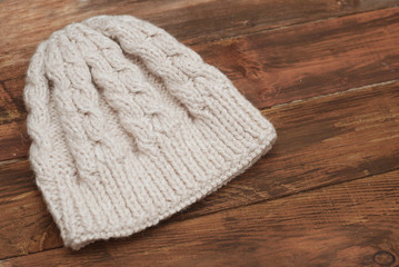Obraz na płótnie Canvas Close-up of beautiful warm ivory knitted hat. Knitted warm handmade hat with beautiful ornament on wooden background.