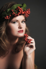 Fototapeta premium Sexy woman in autumn leaves and a wreath of mountain ash