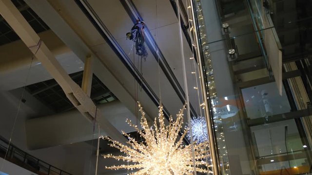 Industrial climber mounts Christmas decorations in the unsupported space in the shopping center