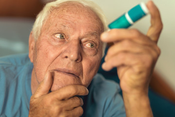 Senior man using eye drops, prevention of eye diseases