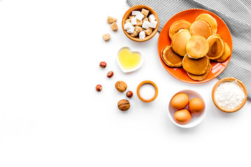 Cooking american pancakes. Ingredients, cakes, nuts and honey on white background top view copyspace