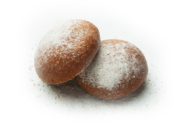 Two fresh black bread rolls with sesame seeds isolated on a bamboo background.